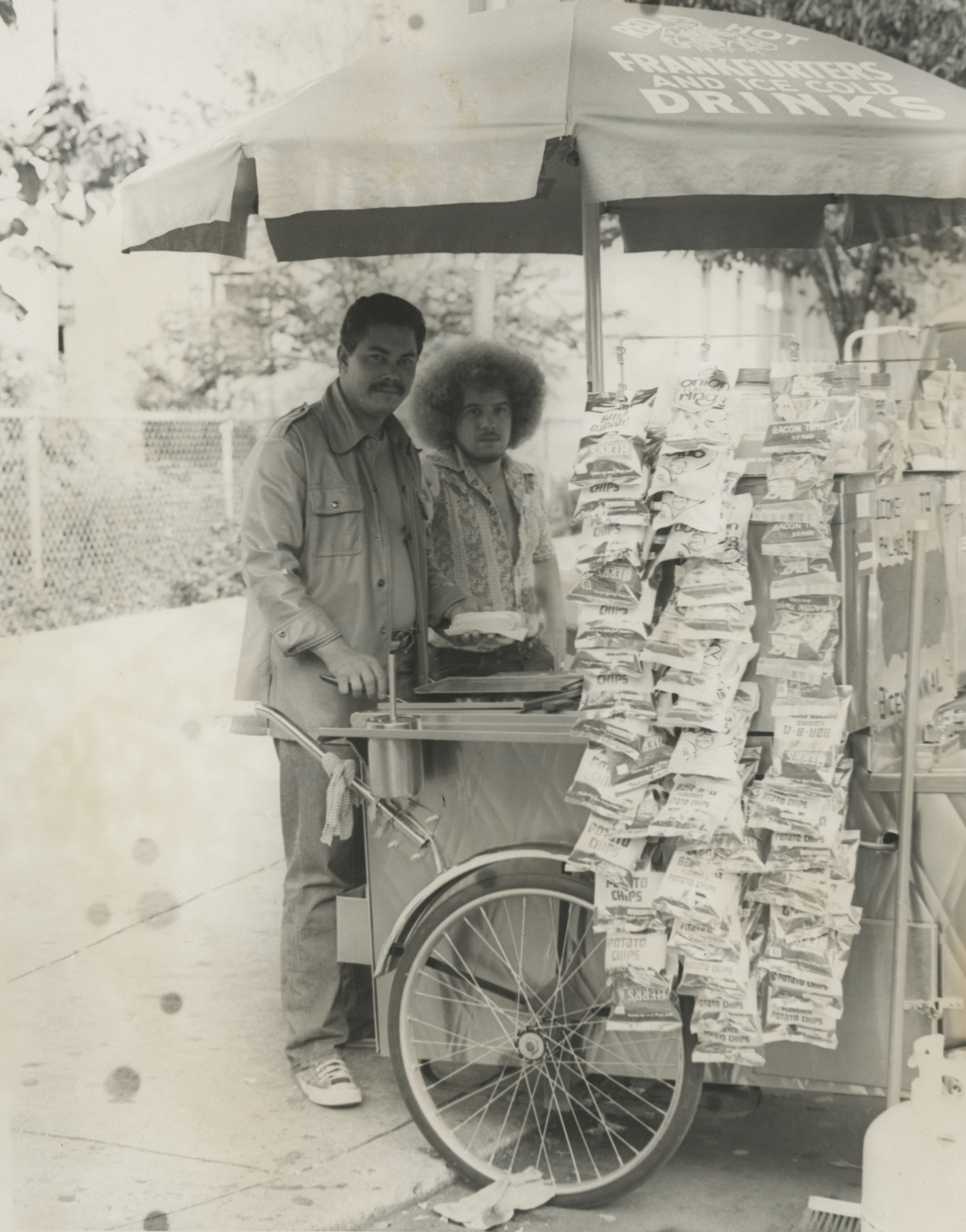 Two men stand at a street vendor cart