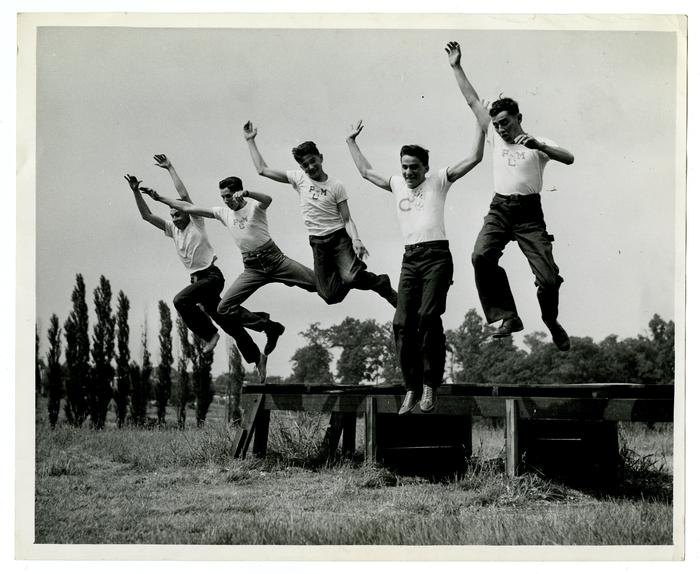 Group of servicemen jumping off bench, WWII
